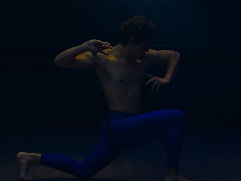 Athletic person stretching hands towards the blue neon sky.